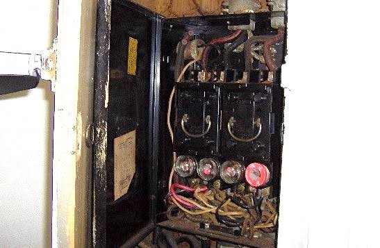 Tableau électrique ancien à Douala avec fusibles à cartouche et fils non protégés, installation dépassée