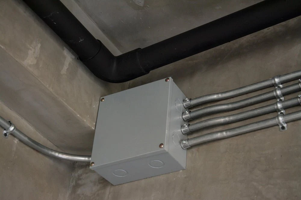 Électricien posant des boîtes d'encastrement et gaines dans les murs d'une maison en construction à Douala